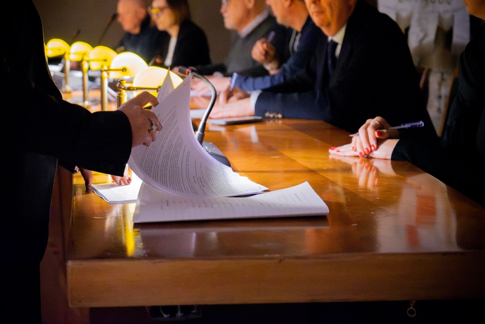Two people reviewing and signing documents at an office desk in Italy