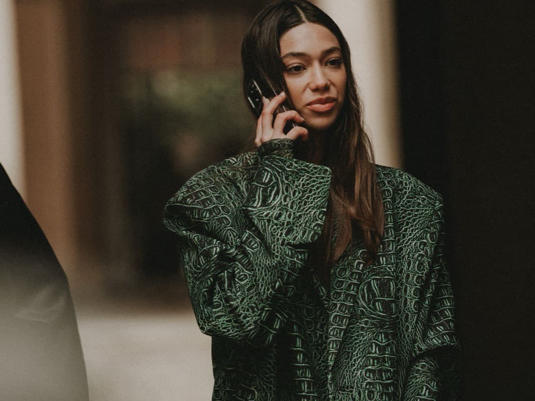 A woman talking on her phone while walking along a city street in Milan