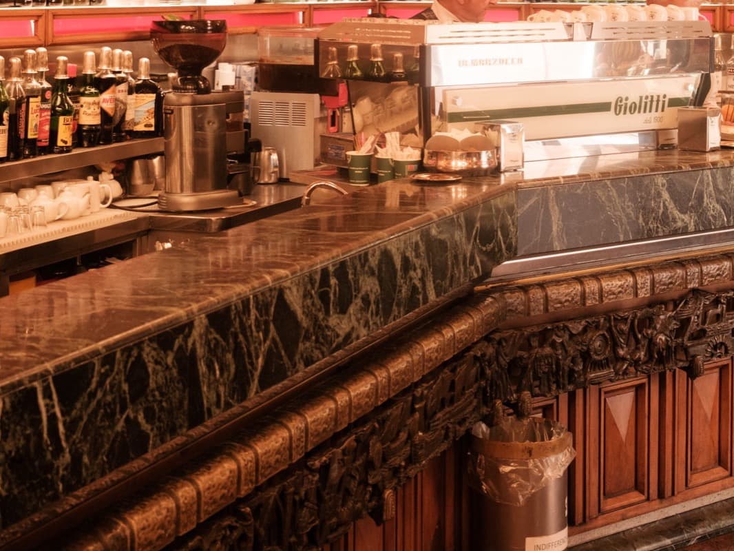 The counter of a traditional Italian coffee bar with vintage decor and bottles on the shelves